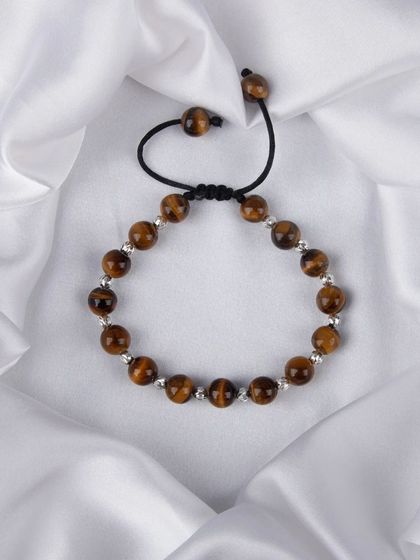 A tiger's eye beaded bracelet with an adjustable cord, shot on white satin.