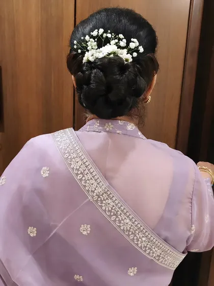 A classic and elegant braided bun, beautifully decorated with fresh baby's breath. This is a timeless hairstyle that works wonderfully for mothers of the bride or for any guest wanting a sophisticated look.