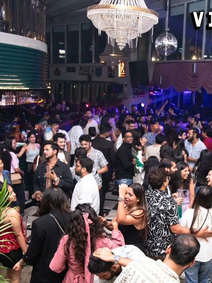 A wide shot of the party at Sarjapur Social. The venue's modern decor, including the grand chandelier, combined with my music, creates a chic and lively nightlife experience.