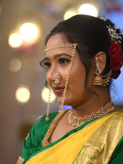 This profile shot captures the elegance of the bride's makeup and hairstyle. The red roses in her hair add a classic touch to the traditional Maharashtrian look.