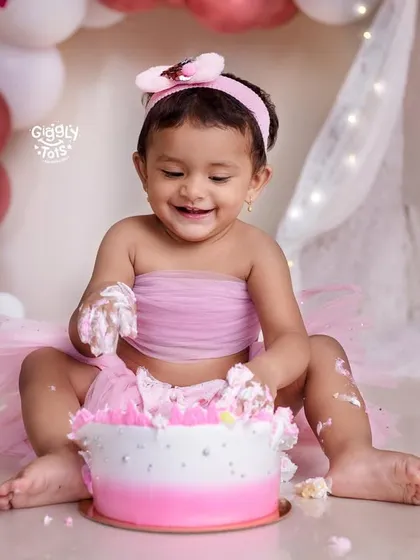 This little girl is having a blast digging into her pink ombre cake during her butterfly-themed cake smash.