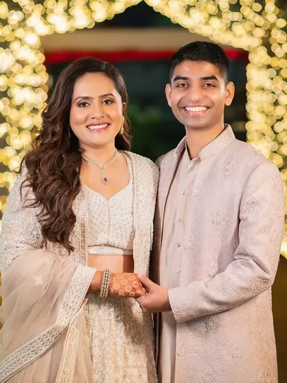 This couple's Sangeet look is pure elegance. The bride's makeup is soft and glowing, with her hair in romantic waves, perfectly matching the dreamy, fairy-light ambiance.