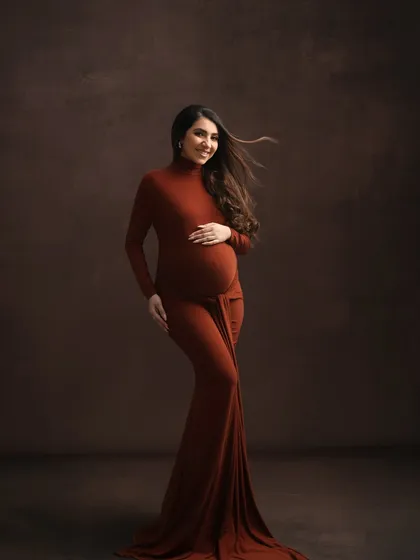 My studio can transform to match any mood. Here, a rich, earthy-toned gown and a darker, textured backdrop create a fine-art portrait that feels both powerful and intimate, focusing on the beautiful silhouette of pregnancy.