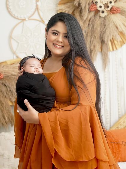 A mother's loving embrace. She holds her sleeping newborn daughter close in our warm, boho-inspired studio, creating a peaceful and beautiful portrait.