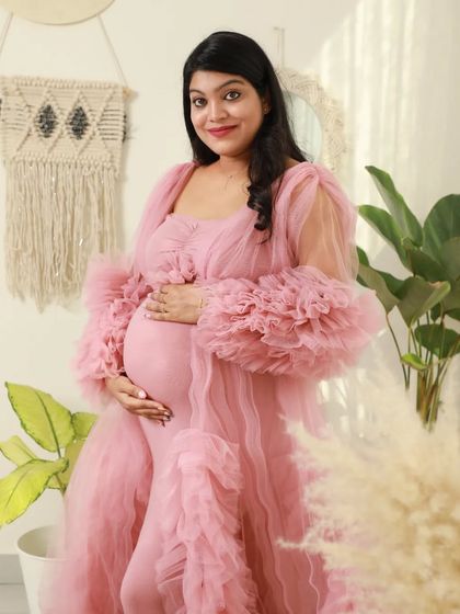 A beautiful and welcoming portrait of a mom-to-be in a pink gown. Her warm smile and the cozy studio setting make this photo feel so inviting.