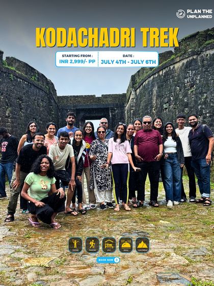 A large group poses in front of a historic fort on the Kodachadri trek.