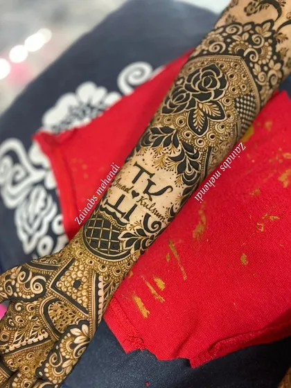 The full arm design for Kulsum, with the couple's initials taking center stage on the forearm.