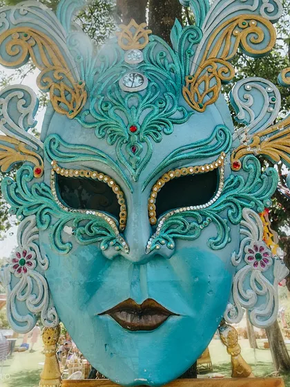 An oversized, ornate masquerade mask in shades of blue and gold, serving as a stunning and artistic decor piece for the festival-themed event.