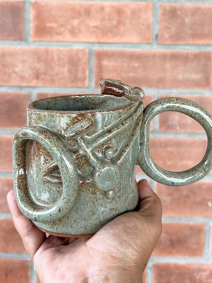 This incredibly detailed mug with interlocking rings and a dragon accent was made by a talented student. It's a true work of functional sculpture.