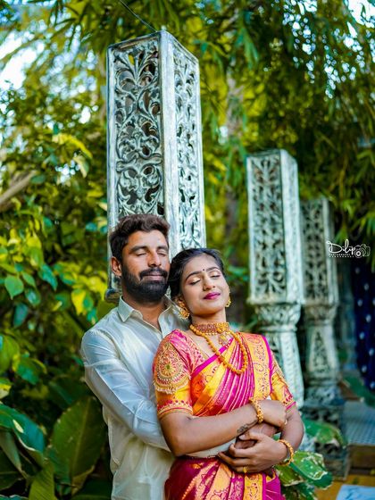 An intimate moment between a couple in traditional attire, framed by white carved pillars.