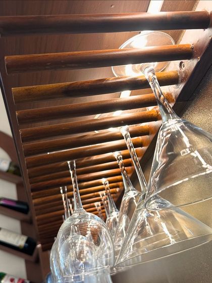 A close-up of the custom-built wooden glass rack. This simple yet elegant solution keeps glassware organized and easily accessible, adding a professional touch to the home bar.