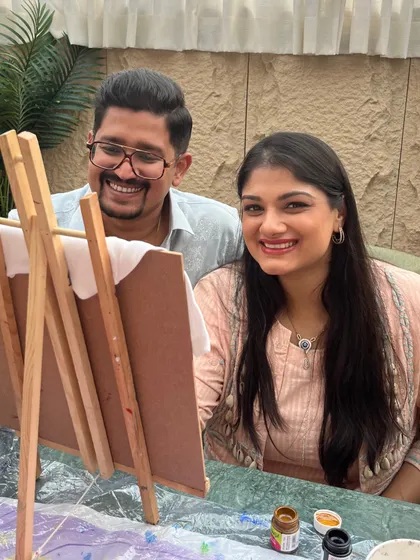 A couple shares a smile while working on a painting at their baby shower. My art parties are all about creating joyful memories together.