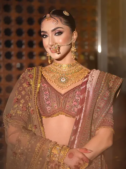 A full portrait showcasing the complete look, where the hairstyle with traditional swirls complements the majestic makeup and heavy gold jewelry.