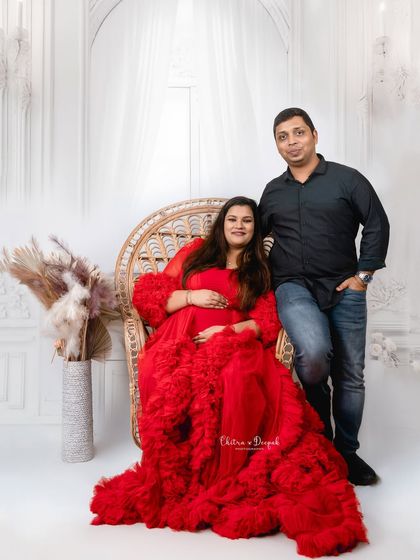 A classic seated portrait of the couple. Her bold red gown and his casual style create a beautiful visual balance.