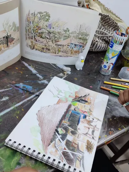 A young student works on a detailed landscape drawing with color pencils, learning to recreate a complex scene from a reference photo.