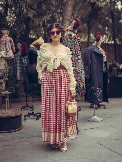A full-length street-style shot that captures the complete vintage-inspired outfit in the context of the event's decor.