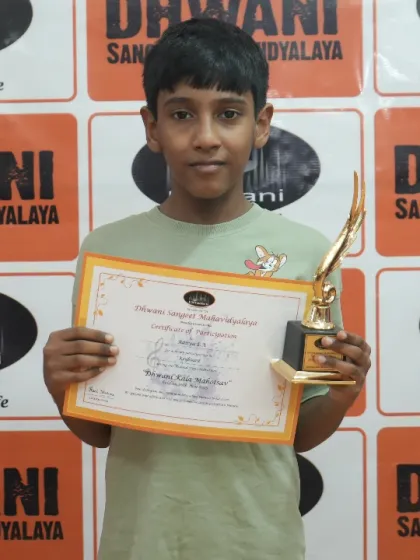 A student proudly holds his certificate and trophy.