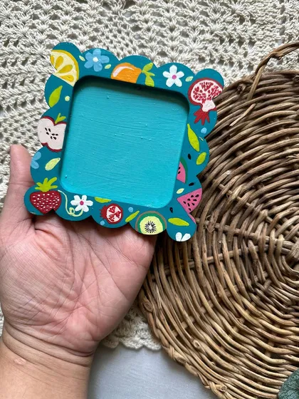 This cute, scalloped-edge photo frame magnet is decorated with a variety of colorful fruits.