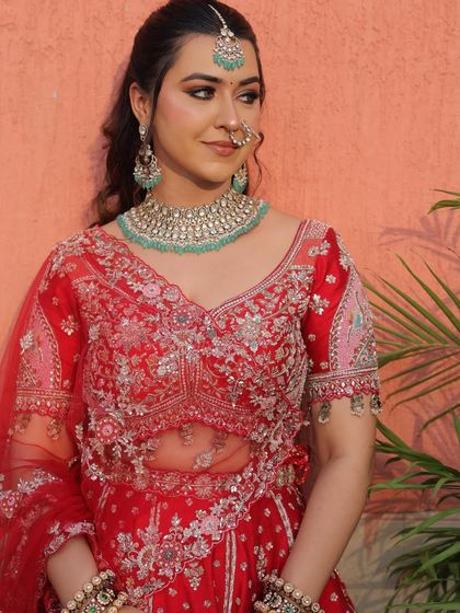 Another portrait shot showing the intricate details of the red bridal blouse. The sheer panel on the neckline adds a modern touch to the traditional design.