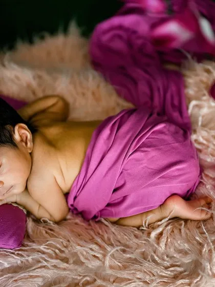 A classic side-lying pose on a fluffy pink rug, with a beautiful magenta wrap.