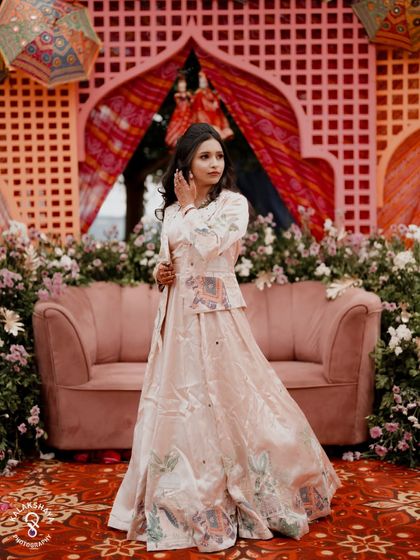 A full-length portrait of the bride at her Sangeet, showcasing her beautiful, flowing lehenga.