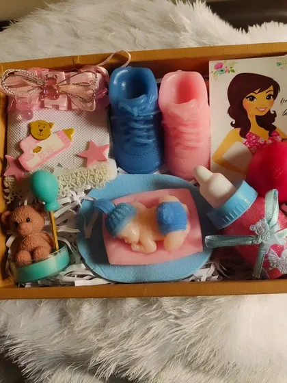 The contents of the baby shower hamper, including a sleeping baby soap, shoe soaps, and a teddy candle.