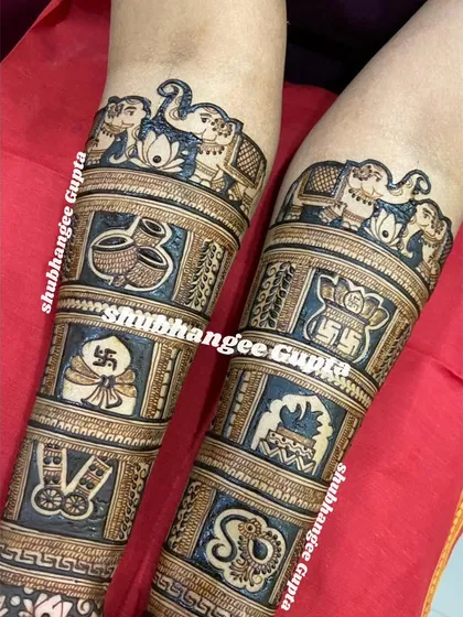 A close-up of the story elements on a bridal mehndi. This design includes panels with elephants, kalash, swastika, and the couple's initials.