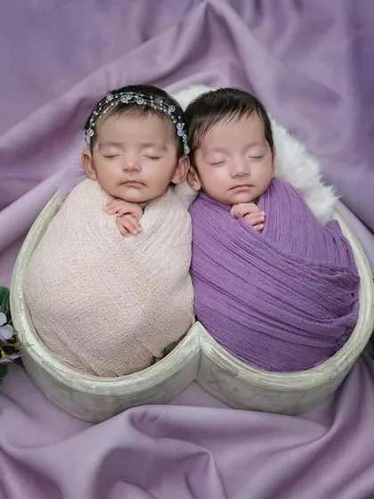 A perfectly symmetrical portrait of the newborn twins. This shot showcases the careful posing and styling involved in a twin photoshoot to create a balanced and artistic image.