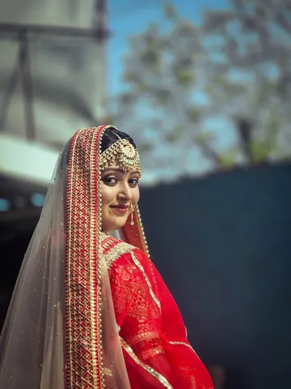 A classic bridal portrait. This student's work highlights a soft, radiant makeup look complemented by a traditional passa and dupatta, showcasing skills in both makeup and styling.