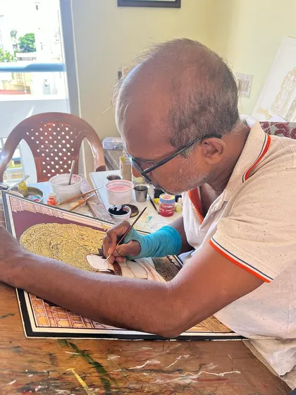 A focused moment at my desk, painting the intricate details that define the Mysore style.