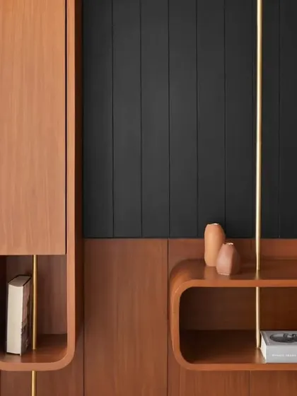 Detail of the custom TV unit, where teak wood veneer and brass verticals create a sophisticated storage solution. The rounded shapes are a signature of the Japandi theme, softening the modern design.