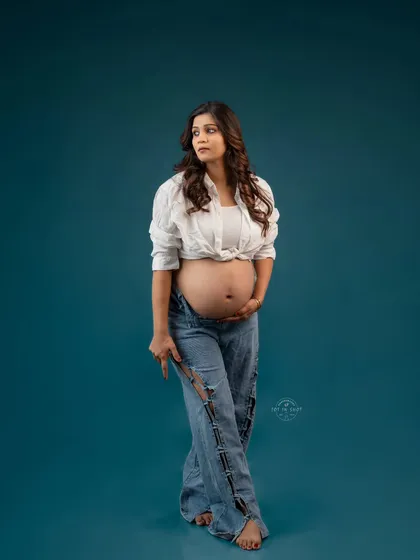 Celebrate your pregnancy with confidence and style. This modern maternity portrait in jeans and a crop top showcases a chic, relaxed, and contemporary approach to capturing your beautiful bump.