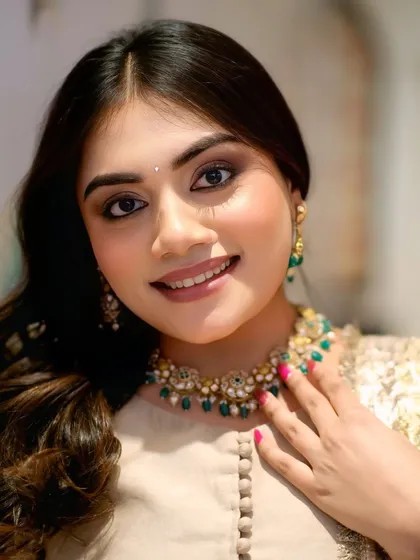 A close-up portrait of a model, perfect for showcasing jewelry and makeup. The direct eye contact and warm smile make the image very engaging.
