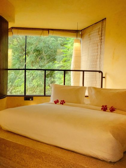 A cozy, sunken bed nook with a large window looking out into the dense greenery, making you feel completely immersed in nature.