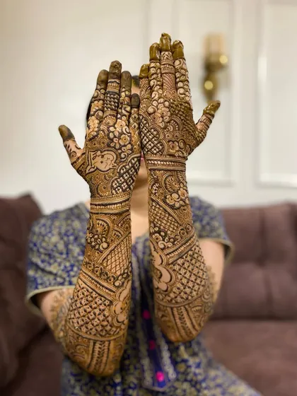 A full view of a stunning bridal mehendi, with the bride peeking through her hands. A moment of joy and anticipation.