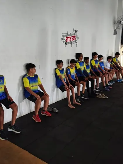 Players perform wall-sits during a strength and conditioning session in the on-campus fitness center. This highlights our focus on building the physical strength and endurance essential for a modern footballer.