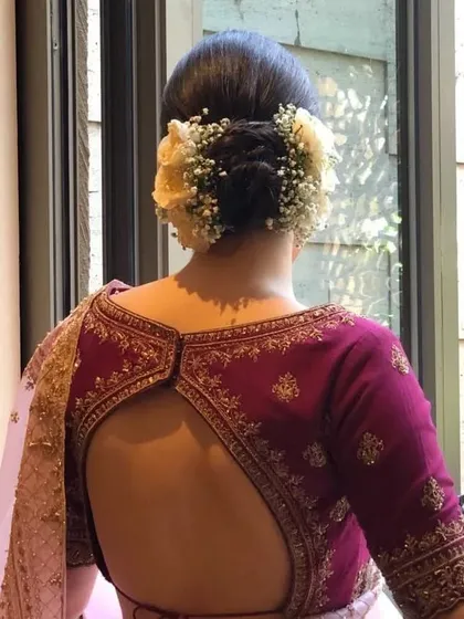 A clear back view of a braided bun with fresh flowers. This updo is a beautiful option for brides who want a touch of tradition with a romantic flair.