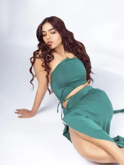A full-body seated pose that showcases the entire green dress. This type of shot is great for lookbooks as it shows how the fabric drapes.