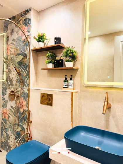 Even smaller details contribute to the overall feeling of a space. This bathroom design uses a bold, tropical wallpaper as an accent, paired with a vibrant blue basin and brass fixtures to create a unique and refreshing aesthetic.