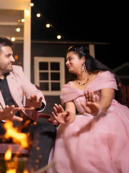 Fun and playful moments from a pre-wedding shoot. This couple shares a laugh by the fire pit, with the bride in a soft pink gown.