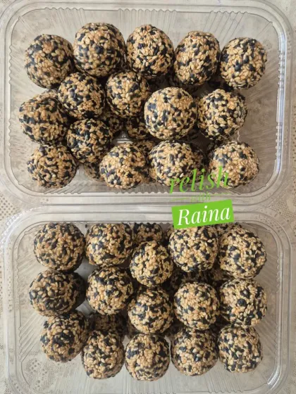 Two clear containers packed with mixed Til Laddoos. This packaging makes it easy to see the quality and freshness of the product.