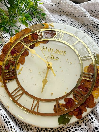 An angled shot of the varmala wall clock, showing how the light catches the gold details on the clock hands and numerals.