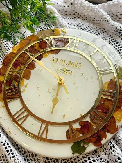 An angled shot of the varmala wall clock, showing how the light catches the gold details on the clock hands and numerals.