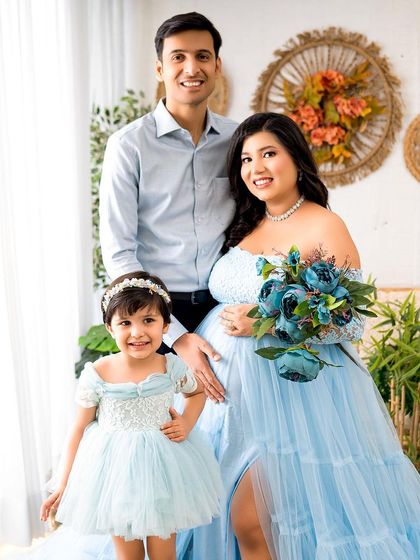 A perfect family portrait with everyone looking radiant. The coordinating blue outfits create a harmonious and visually pleasing image.