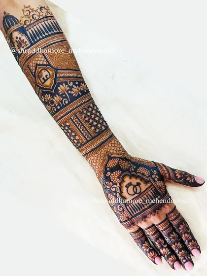 A side view of a full bridal arm, showing how the design wraps around. This piece features palace architecture, an elephant, and engagement rings.