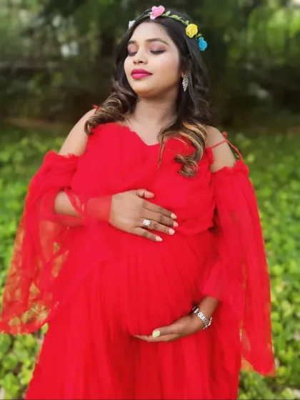 This vibrant red gown features a wide, ruffled trail and off-the-shoulder sleeves, offering a bold and glamorous look for an outdoor maternity shoot.