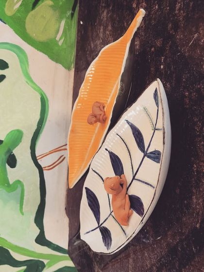 These leaf shaped ceramic trays, one unpainted and one with a simple, elegant design, are perfect for holding trinkets or as decorative pieces.