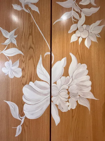 A detail of the white wildflower mural painted on wooden wardrobe doors. The artwork flows across the two doors, creating a unified composition when closed.