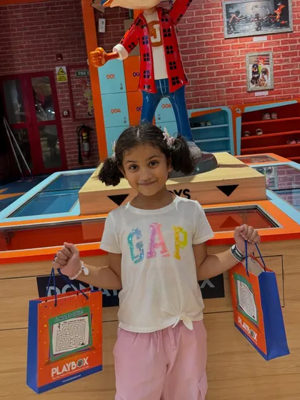 A happy girl posing with her goody bags after a fun-filled Sunday at our play area.