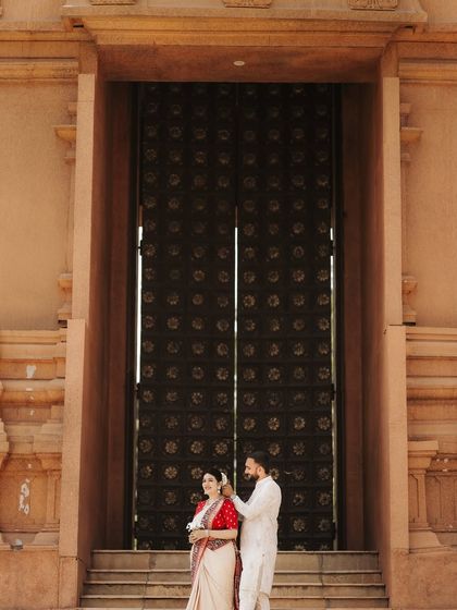 Framed by a massive, ornate doorway, the couple shares a quiet moment. This composition emphasizes the grandeur of the heritage location while keeping the focus on their interaction.